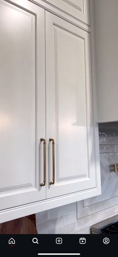 a kitchen with white cabinets and gold pulls on the door knobs that are brass