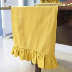 a table with a yellow cloth on it and a bowl of fruit in the background