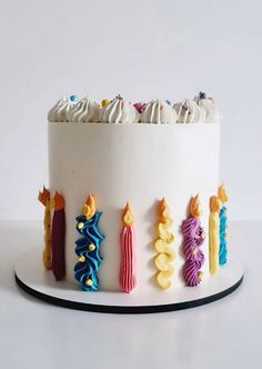 a white cake decorated with colorful icing and candles