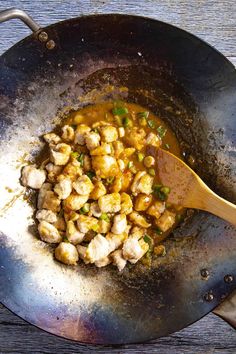 chicken and vegetables cooking in a wok with a wooden spoon