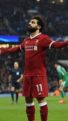 a soccer player is standing on the field with his arms spread out and looking up