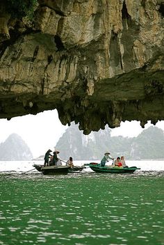 several people in small boats on the water near an island with large rocks and cliffs