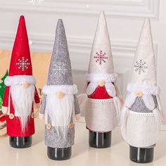 three wine bottles decorated with christmas gnomes and snowflakes are sitting on a table