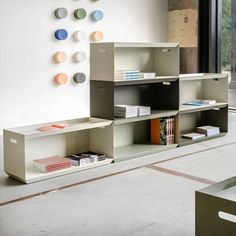 a book shelf with many books and magazines on it in front of a large window