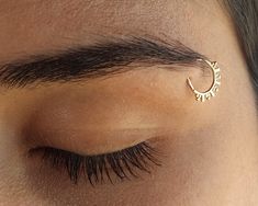 a close up of a person's eye with a gold nose ring on it