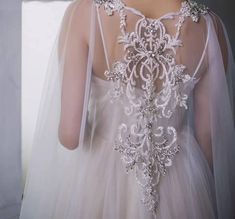 the back of a woman's wedding dress with an intricate beaded design on it