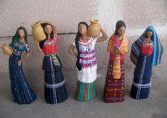 four figurines are standing next to each other on the sidewalk and one is holding a jug