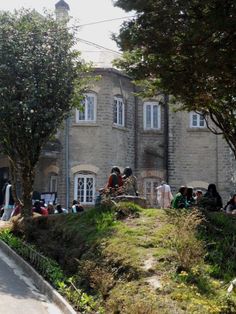 people sitting on the grass in front of a building