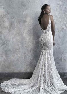 a woman in a white wedding dress is standing against a wall with her back to the camera