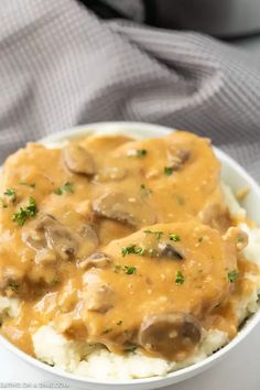 a white bowl filled with mashed potatoes covered in gravy