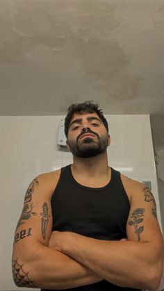 a man with his arms crossed standing in front of a mirror and looking up at the ceiling