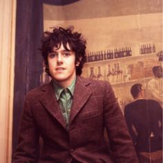 a man wearing a suit and tie standing in front of a wall with pictures on it