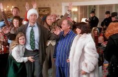 a group of people standing next to each other in front of a christmas tree with santa hats on