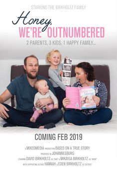 a man and woman sitting on a couch with two children holding books in front of them