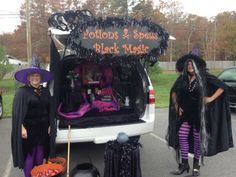 two women dressed up in halloween costumes standing next to a van with witches on it