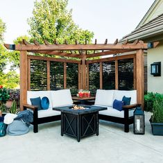 an outdoor living area with white couches and blue pillows on the patio, next to a fire pit