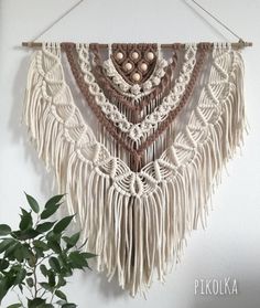 a white wall hanging with macrami beads and tassels