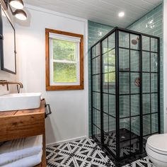 a bathroom with a glass shower stall next to a sink and toilet in the corner