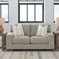 a living room scene with focus on the couch and two lamps in front of the window