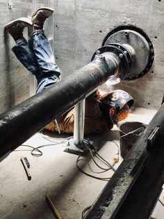 a man laying on the ground with his feet up next to a pipe and some tools