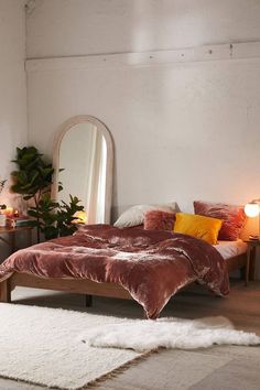 a bedroom with a bed, mirror and plants