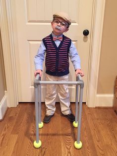 a little boy standing in front of a door wearing goggles and holding a walker