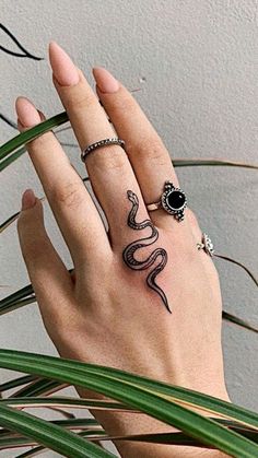 a woman's hand with a snake tattoo on it and a ring in the middle