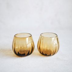 two yellow glass cups sitting on top of a white table