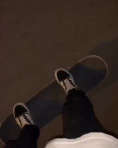 a person standing next to a skateboard on the ground with their feet in the air