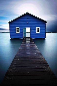 a blue house sitting on top of a wooden pier