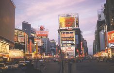 a busy city street filled with lots of tall buildings and neon signs at night time