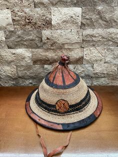 a hat sitting on top of a wooden table next to a stone wall in the background