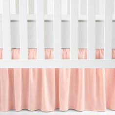 a white crib with pink bedding and curtains