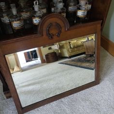 a mirror sitting on the floor in front of a shelf filled with jars and other items