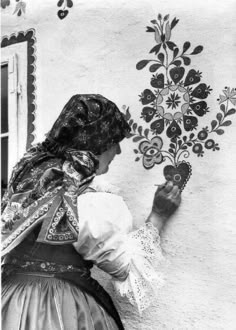 an old photo of a woman painting flowers on the wall