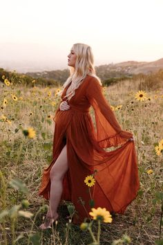 a woman in an orange dress is standing in a field full of sunflowers