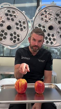 a man sitting at a table with two apples in front of him and an apple on the tray