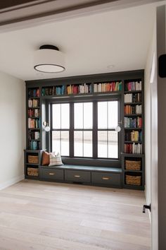 an empty room with bookshelves full of books and baskets on the windowsill