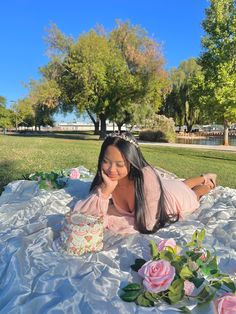 a woman laying on top of a blanket with a cake in front of her face