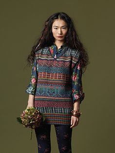 a woman standing in front of a green wall holding a flower pot and wearing leggings