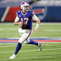 a football player is running with the ball in his hand and wearing a helmet on