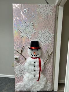 a door decorated with a snowman wearing a top hat and red scarf, standing in front of a pink background