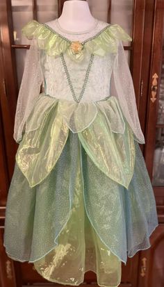 Disney Store Exclusive Size XS 4/5 Tinker Bell Deluxe Dress Up Gown. 3pcs Costume Outfit includes Dress, wand and crown. Perfect for Halloween, Dress up or for a Tinker Bell themed birthday party!🥳The stunning long sleeved gown has been made with every attention to detail. From its sparkling floral glittery filigree overlay bodice, sheer glittered long sleeves and neckline, Golden Tinker Bell cameo with gems, glittered ricrac trim and soft sheer petal collar. The bodice back is green polyester Green Long Sleeve Fancy Dress, Green Long Sleeve Dress For Fancy Occasion, Fitted Long Sleeve Green Princess Dress, Green Long Sleeve Fitted Princess Dress, Green Fitted Princess Dress For Costume Party, Green Fitted Long Sleeve Princess Dress, Green Long Sleeve Princess Dress, Adult Tinkerbell Dress, Tinkerbell Dress Women