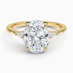 a yellow gold ring with an oval cut diamond in the center and three smaller diamonds on each side