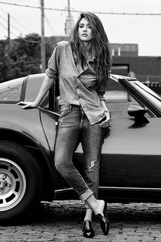 a woman leaning on the hood of a car