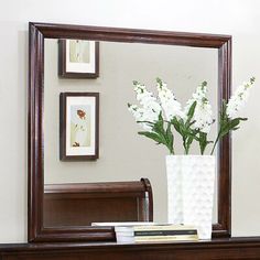 a vase with flowers in it sitting on a table next to a mirror and books