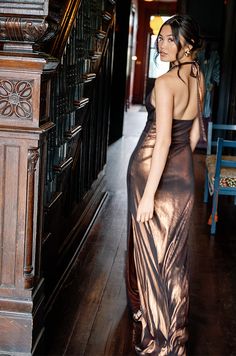 a woman in a long dress is standing on the stairs and looking at something behind her