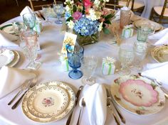 the table is set with plates, silverware and flowers in vases on it