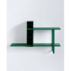 a green shelf sitting on top of a white wall next to a black object in the shape of a rectangle