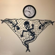 a clock mounted to the side of a wall next to a netted triangle with skeletons on it